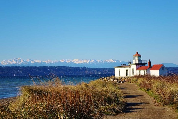 West Point Light is a lighthouse at Discovery Park in Seattle on Puget Sound\'s Elliott Bay. A hiking path leads to the lighthouse & beautiful view of snow capped Olympic Mountains on clear winter day.