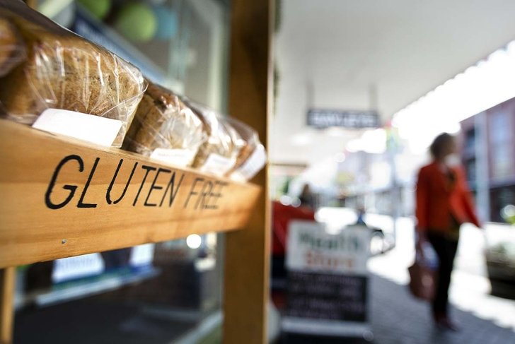 AUCKLAND, NZ - OCT 09 2013:Woman passing by Gluten free bakery. Gluten-free food is normally seen as a diet for celiac disease, nearly 1 out of every 133 people has celiac disease.