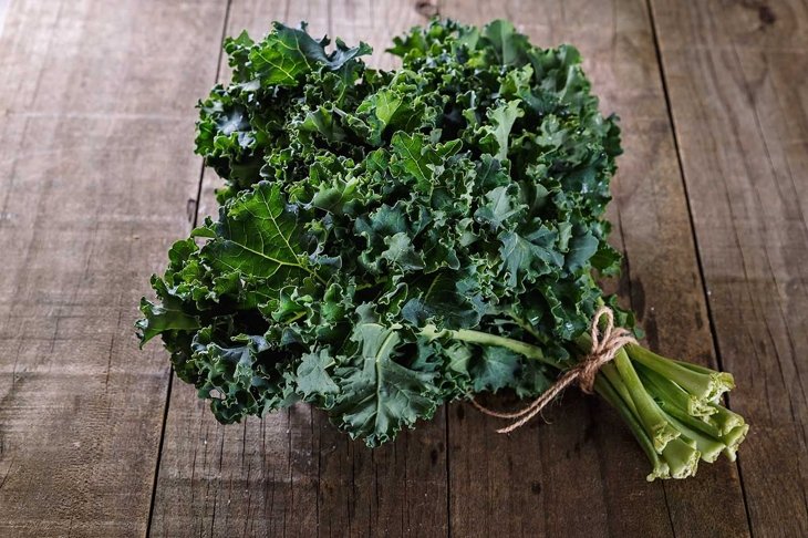 Bunch of organic kale on a rustic wooden background. Selective focus