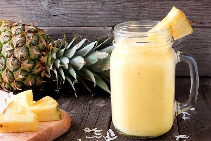 Tropical pineapple smoothie in a mason jar, scene against an old wood background