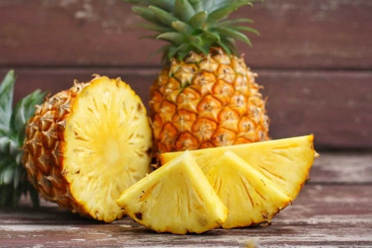 Close up at Sliced and whole of Pineapple(Ananas comosus) on wooden table background.Sweet,sour and juicy taste.Have a lot of fiber,vitamins C and minerals.Food,Fruits or healthcare concept.