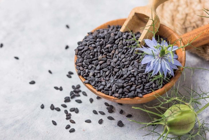 Black cumin seeds with nigella sativa flower on white background