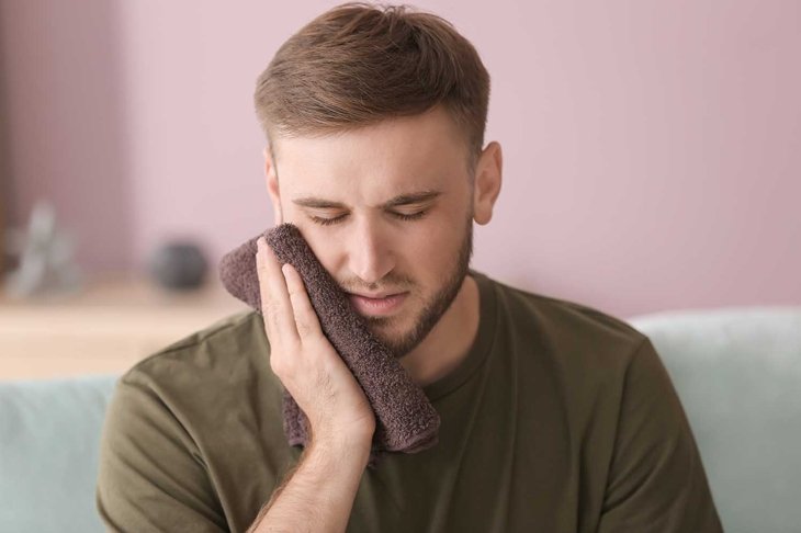 Young man suffering from toothache at home