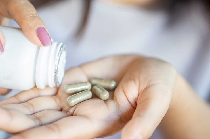 closeup woman hand taking herb medicine tablets