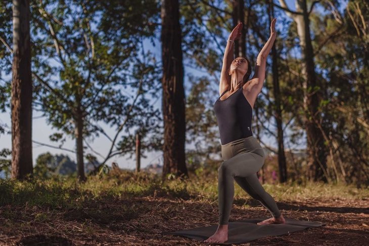 Beautiful brunette yoga woman teacher practicing deep breathing in the wild nature