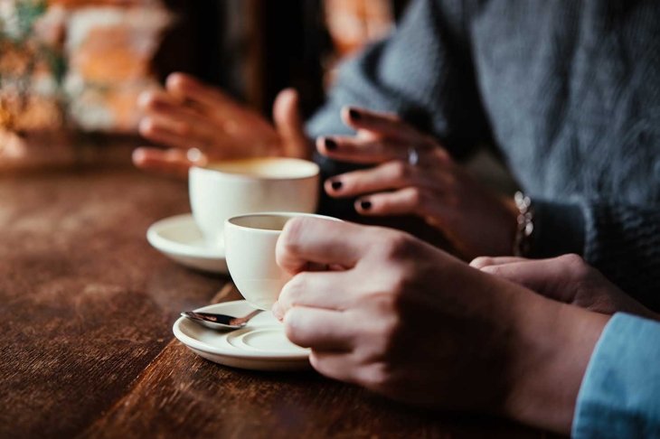 Two women discussing business projects in a cafe while having coffee