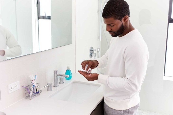 Man In Bathroom Taking Vitamin Supplement Tablets