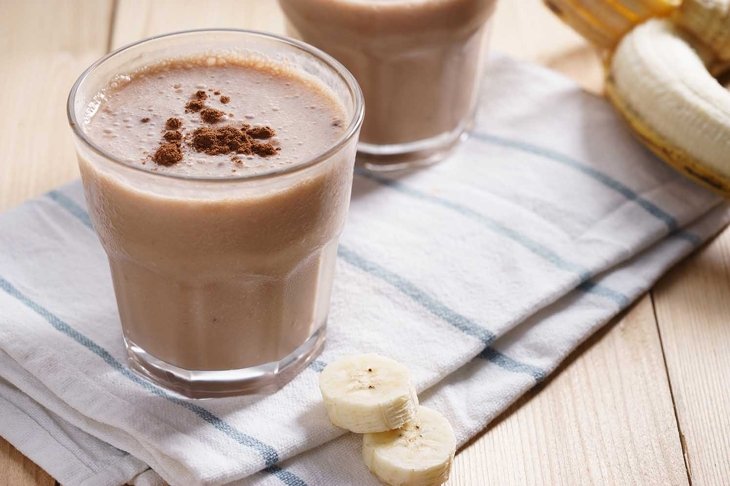 Banana smoothie with cocoa on wooden background