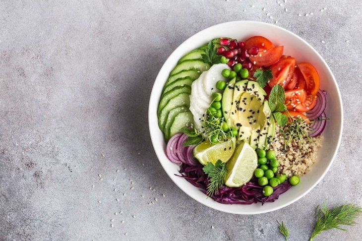 healthy vegan lunch bowl. Avocado, quinoa, tomato, cucumber, red cabbage, green peas and radish  vegetables salad. Top view